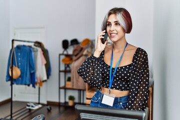 Young caucasian shopkeeper woman smiling happy talking on the smartphone working at clothing store.