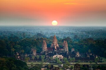 Bird's eye view of the Angkor Wat temple surrounded by greenery at sunset in Cambodia