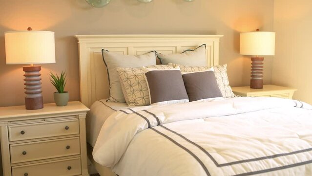 Panning bed with decorative pillows by wooden headboard in bedroom in staging home, house country style with lamps on nightstands
