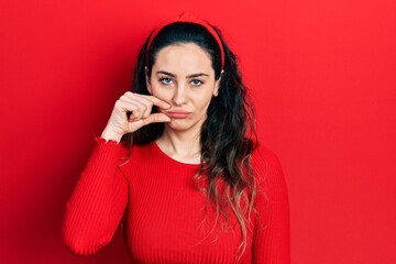 Young hispanic woman wearing casual clothes mouth and lips shut as zip with fingers. secret and...