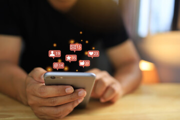 Hands is using on smart phone to use social media to communicate with social community networks, and icons float from the screen to send messages appointments love stars.