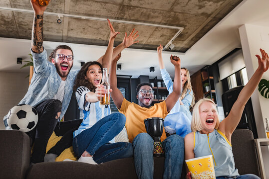 Excited Multicultural Football Fans Celebrate A Goal Score Of Their Team. Friends Gathered Together To Watch The Soccer Football Championship