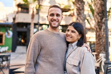 Man and woman couple smiling confident hugging each other standing at street