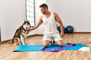 Young hispanic man smiling confident playing with dog at sport center