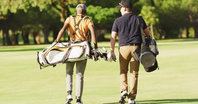 Video of back view of diverse male friends walking on golf field