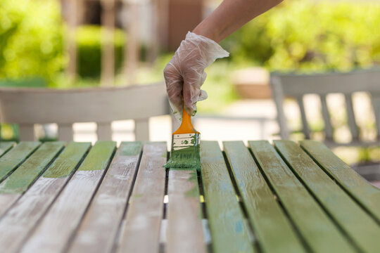 Painting wooden garden table. Painting and caring for wood with oil.  Painting in protective gloves.
