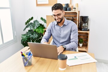 Young arab man smiling confident using laptop working at office