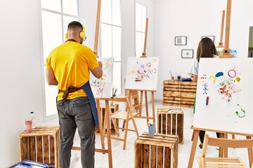 Young hispanic couple smiling happy listening to music and drawing at art studio.