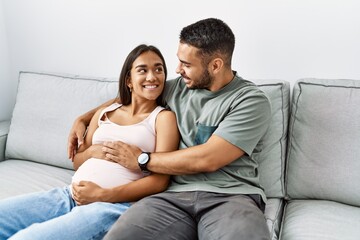 Latin man and woman couple hugging each other expecting baby at home