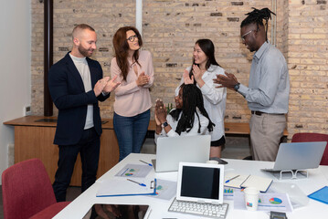 young multiethnic group of entrepreneurs working together for business success or achievement applauding in a work office, multiracial employees applaud excitedly for good news