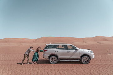 Fototapeta na wymiar Couple pushing the 4x4 car in the desert of Oman.