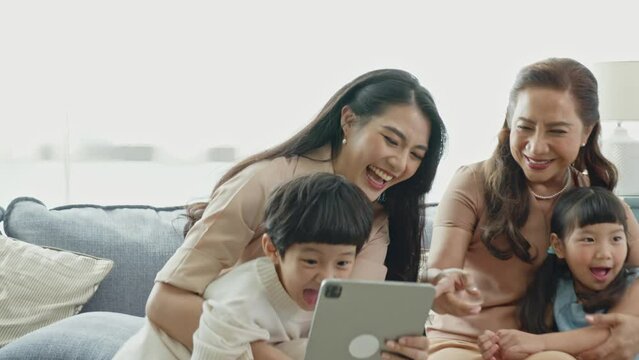 Happy Asian family using digital tablet in living at home, relaxing at home for lifestyle concept.
