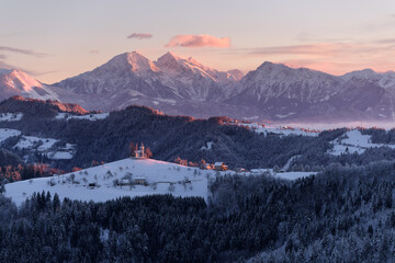 Beautiful winter morning after fresh snow with a tiny church below the mountains.
