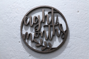 carved dark wooden circle with moons on a gray background for photographing children. eight months