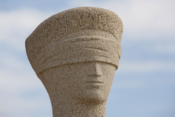 Closeup of a blindfolded statue on a blurred sky background
