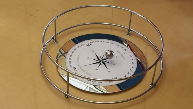 Foucault pendulum swinging on a compass rose. The text in latin "Omnia mutantur, nihil interit" means everything changes, nothing disappears and "Sapere aude" dare to know