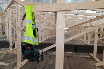 Warning vest for a worker at a construction site. Construction of a wooden frame roof. Carpenter's work clothes