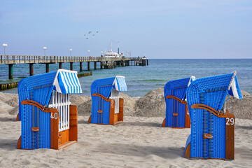 Beach chairs on the Baltic Sea beach in seaside resort town Kühlungsborn in Mecklenburg-Vorpommern, Germany. In the background tourist boat at the pier.