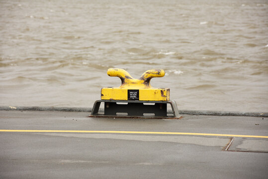 Yellow ship poller on the surface against the sea.