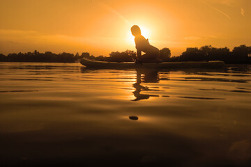 Woman on sup board, paddle boarding at sunset reflection