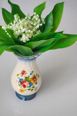 bouquet of lilies of the valley with leaves in a vase or on a table 