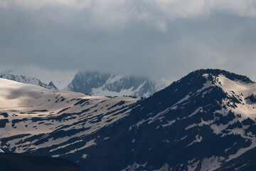 Fototapeta na wymiar Unas cumbres del pirineo cubiertas de nubes bajas y nieve con tono marrón por la calima