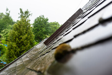 Heavy rain falling on the roof overflowing the gutter with water in rainy weather, visible roof...