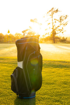 Fototapeta Sunlight streaming through golf clubs in bag on grassy landscape against clear sky at golf course