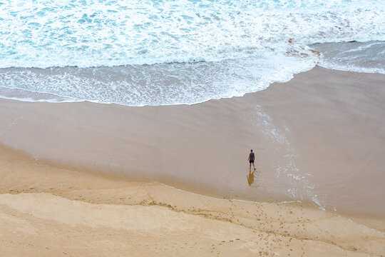 High Angle Shot Of A Person Standing On The Sand Of The Beach Looking At The Sea.