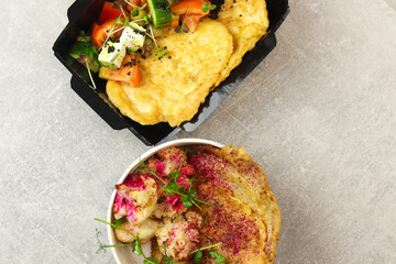Healthy food delivery concept. Beef schnitzel with cauliflower in an eco paper container on a gray...