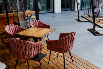 Pink designer chairs stand in a cafe on the street around the table, an outdoor restaurant, a fast...
