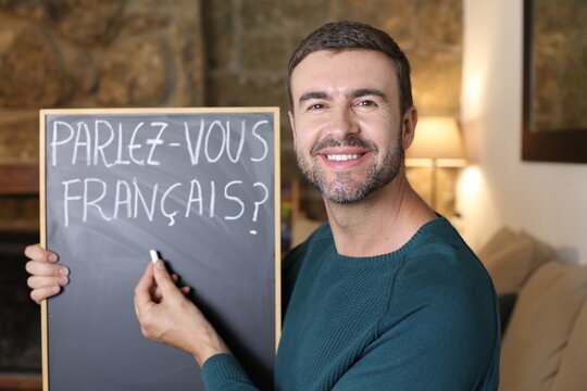 French teacher holding blackboard and French flag. TRANSLATION OF THE TEXT IN THE IMAGE: "Do you speak French?"