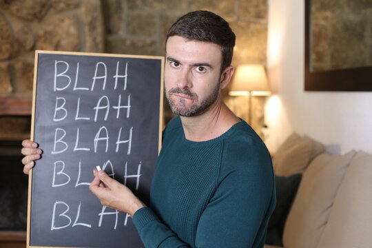 Man holding chalkboard with "blah blah blah" hand written 