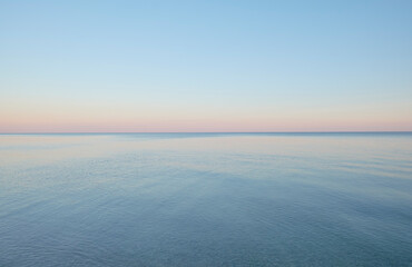 Calm black sea against the sunset sky. As a background.