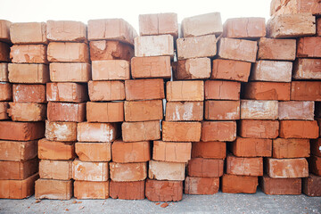 Stack of bricks masonry close up. Process of house building and building materials concept. Red bricks for laying at construction site. Brick wallpaper pattern