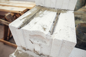 Laying autoclaved aerated concrete blocks with reinforcement and adhesive. Installing white blocks close up. Masonry. Process of house building at construction site