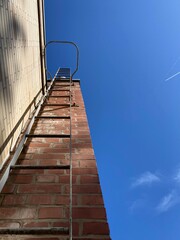 view along a metal ladder on a brick wall against the blue sky