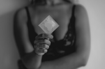The blonde girl holds a closed condom in her hand. Protection against sexual infections. Social...