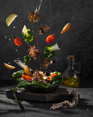 Baby octopus salad with fried potatoes, tomatoes, greens with olive oil, spices. Food levitation photo concept, floating products. Black backgrounds with sunny light. Copy space