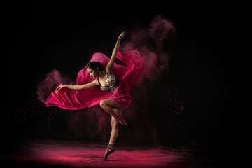 Emotional Southeast Asian ballet dancer in a red dressperforming a move on a black background