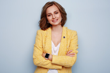Obraz premium Stylish woman in bright yellow clothes smiling and expressing happiness emotions, on blue background. Spring or summer concept. Fashion, make up, and hairstyle. Feminine blog template