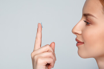 Close up woman putting eye contact lense in or taking out, holding on finger. Eye disorder...