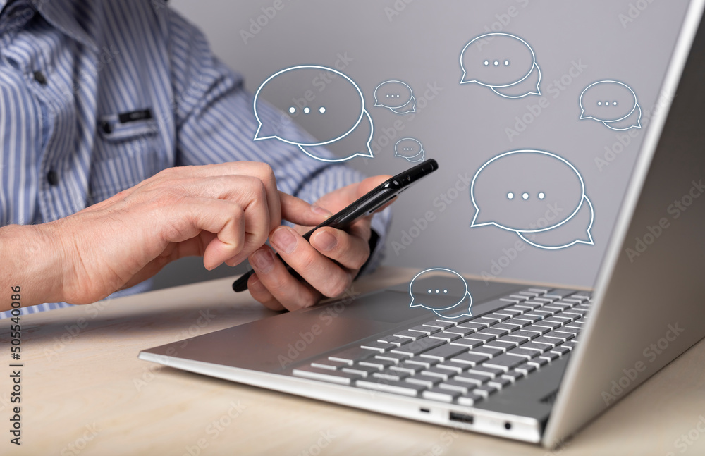 Poster online business communication on messengers. man with phone in hands sitting at table with laptop an