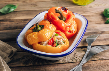 Colorful bell stuffed paprika peppers with meat, rice and vegetables on wooden background