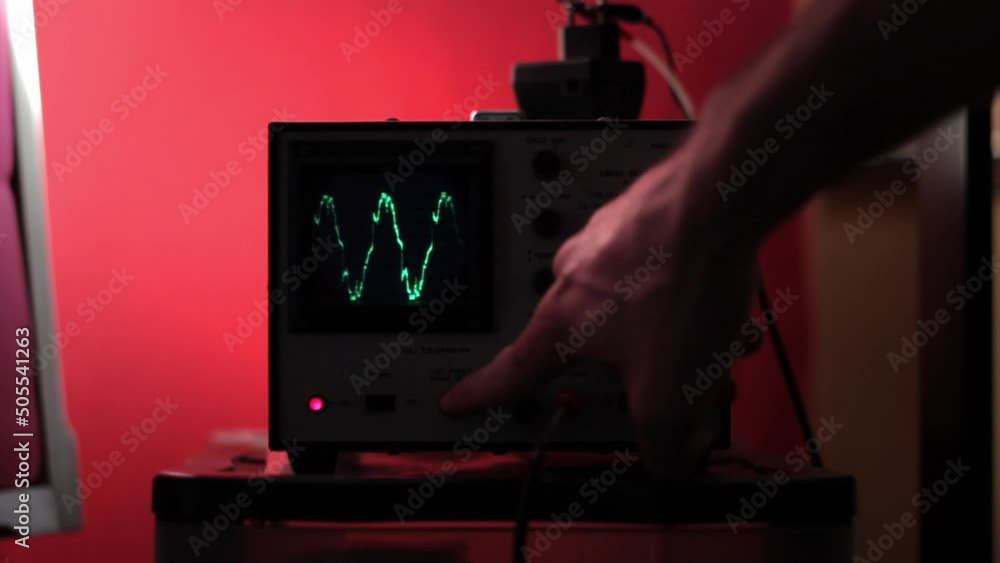 Poster engineer operating a digital oscilloscope in the red room
