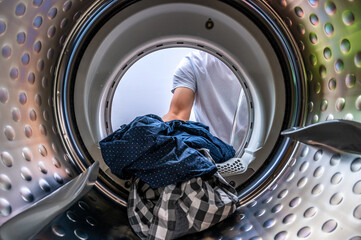 Sicht aus einer Waschmaschine beim Beladen der Waschtrommel mit Wäsche