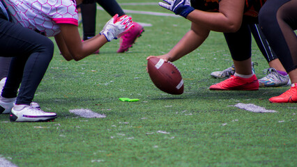 Closeup shot of American football players kicking off  a match on a green field