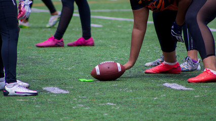 Closeup shot of an American football ball between players hands during a match on a green field