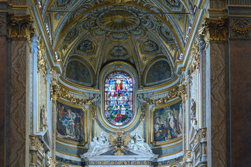 Fototapeta na wymiar The interior of the Catholic Cathedral in Rome with paintings on religious themes and praying parishioners