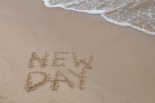 New Day words - drawing on the sand, handwritten on the sea beach sand